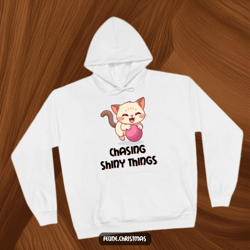 Funny Siamese cat hoodie featuring a joyful cat enthusiastically chasing a Christmas bauble, embodying playful holiday spirit and warmth.