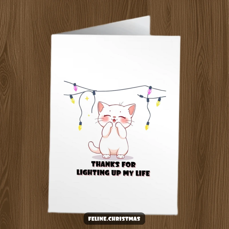 Funny free printable thank you card featuring a white cat playfully batting at a string of twinkling holiday lights.