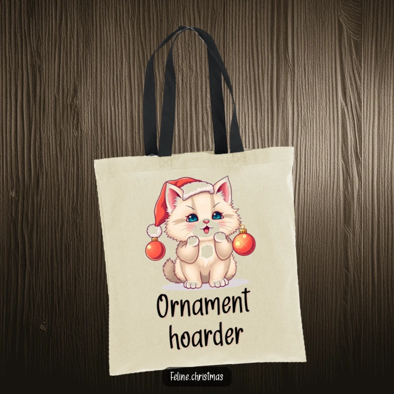 Funny cat tote bag: fluffy kitten sporting a Santa hat playfully attacks a dangling ornament, ideal for holiday shopping.